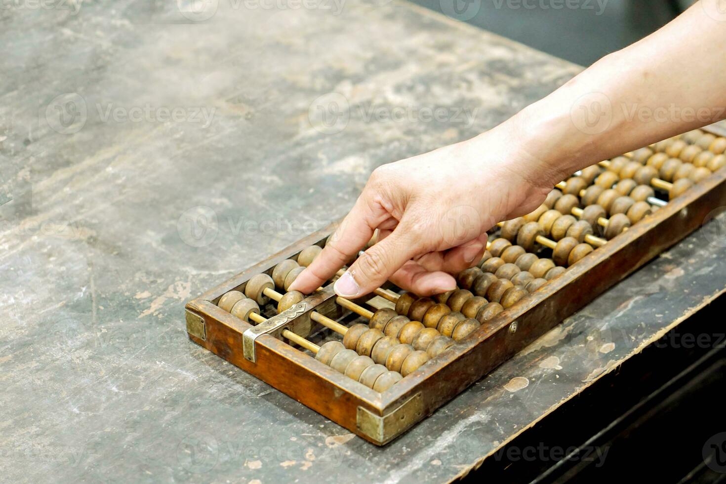 mano de persona jugando y demostración usado de antiguo chino ábaco en antiguo negro de madera mesa. foto