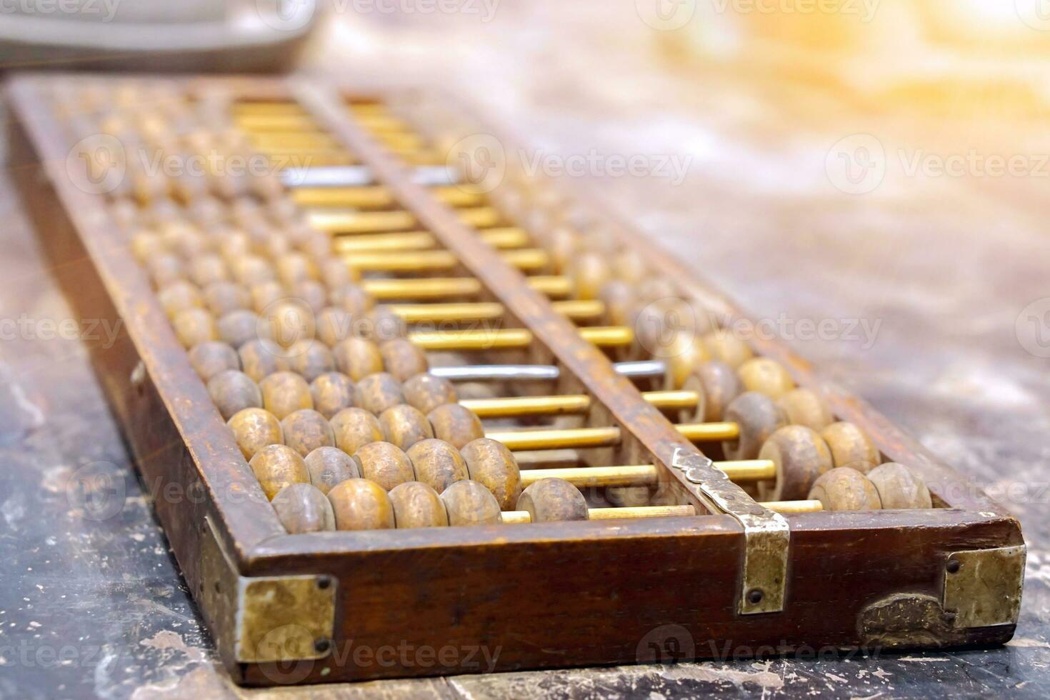 Closeup ancient Chinese abacus on old black wooden table and sun flare background. photo