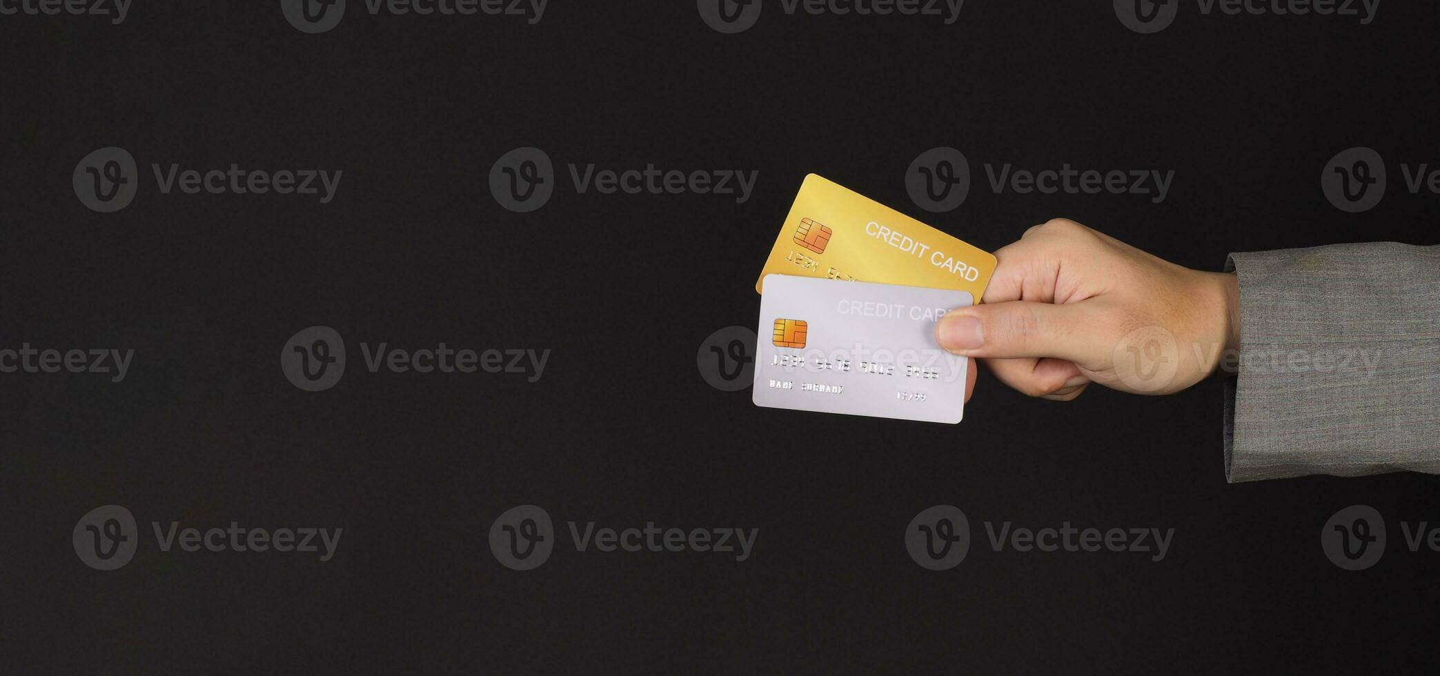mano es sostener dos crédito tarjetas oro y plata color crédito tarjetas aislado en negro antecedentes. foto