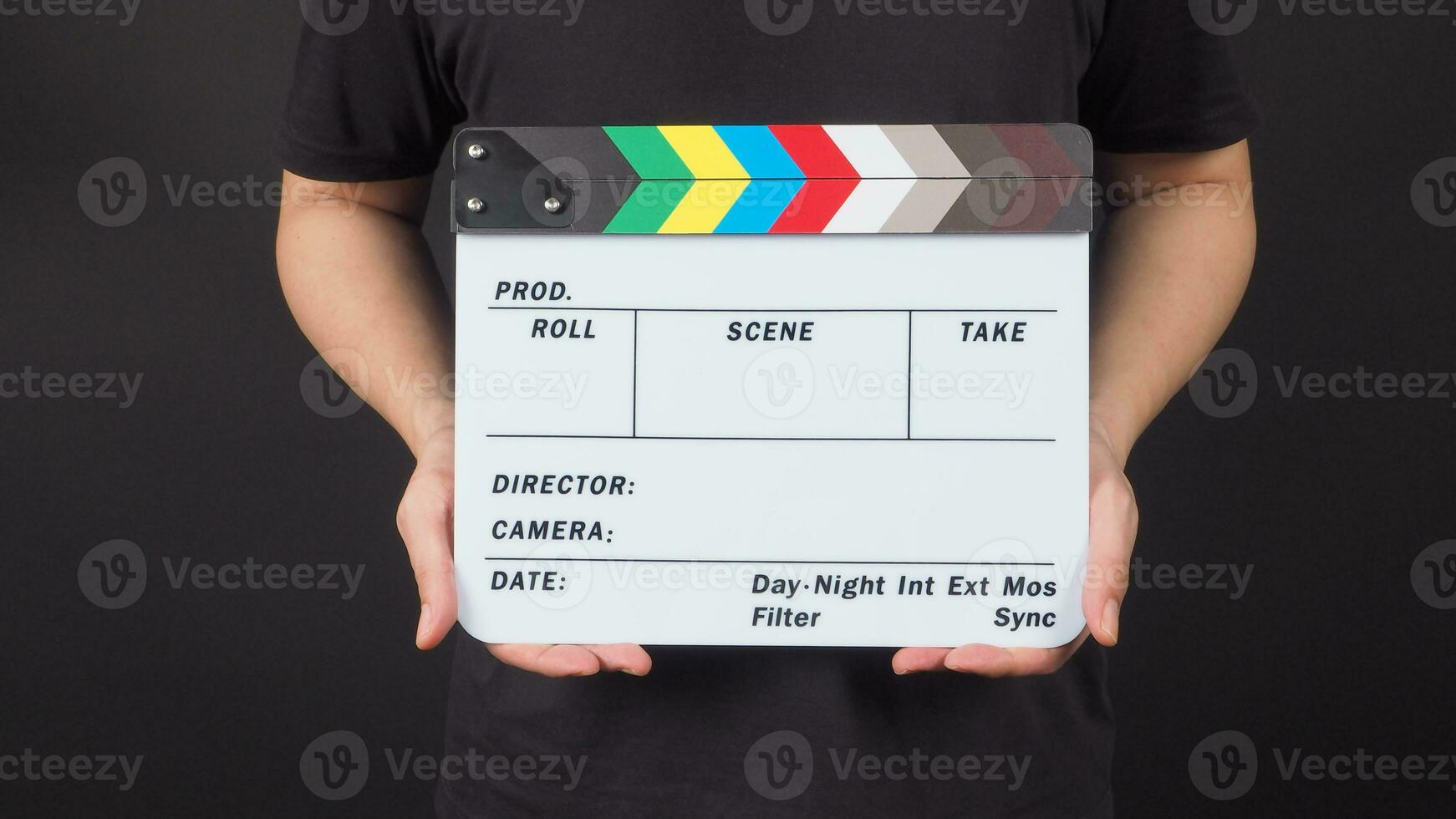 A man is standing with hands is holding Clapperboard or movie slate.It is black background. photo