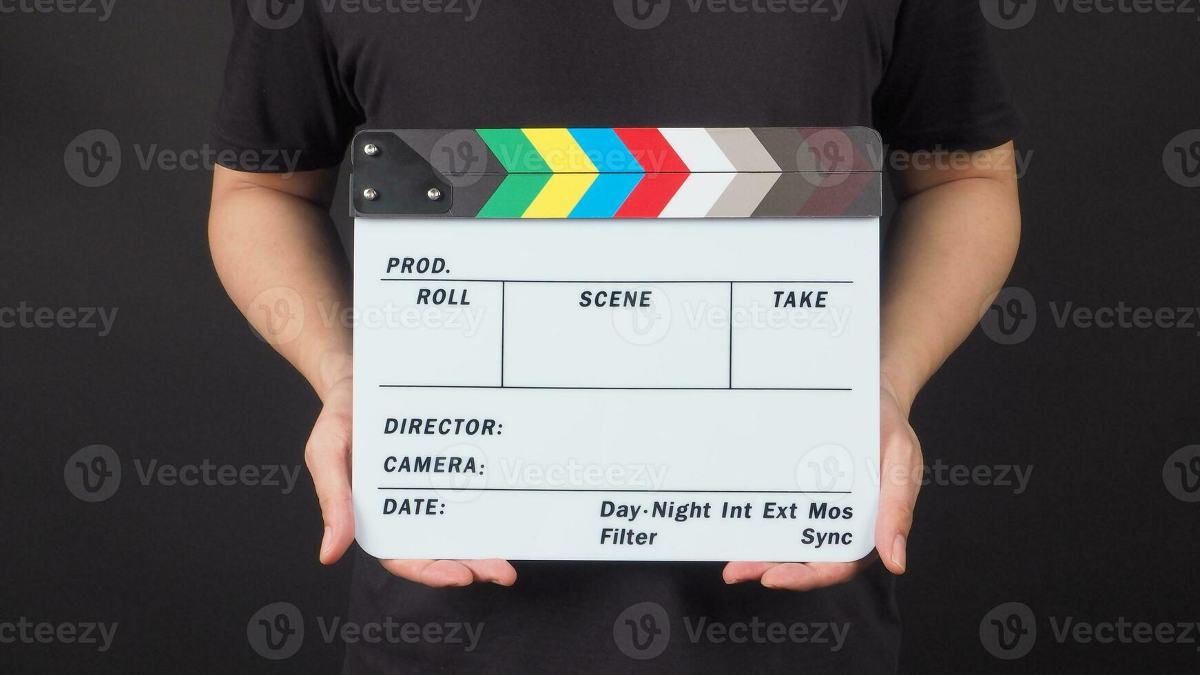 A man is standing with hands is holding Clapperboard or movie slate.It is black background. photo