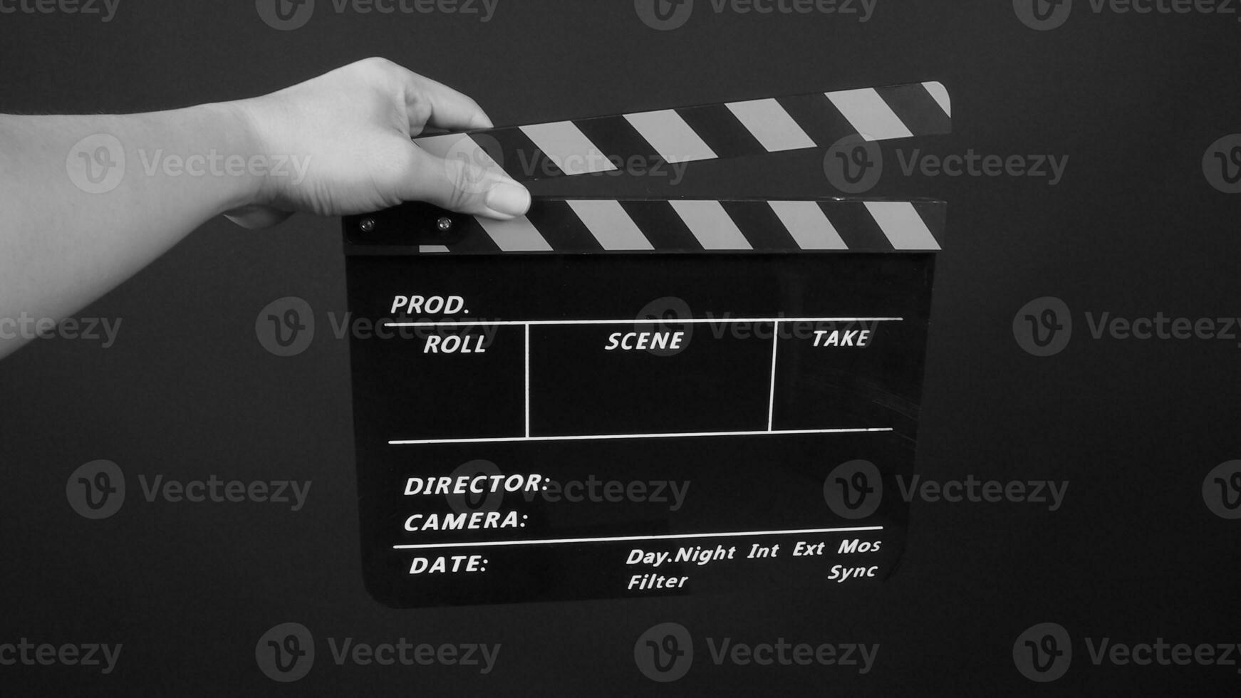 Hand is holding yellow and black color movie slate.It is used in video production and film industry on black background. photo