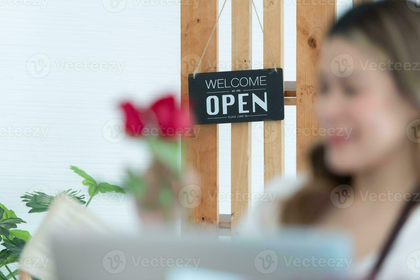 Woman using laptop with open sign in floral shop. Business concept. photo