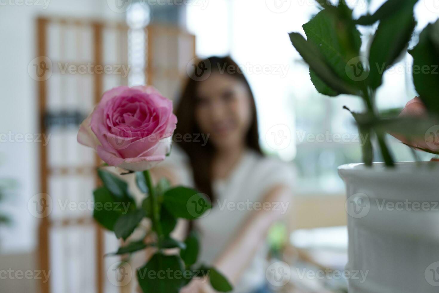 Beautiful young asian woman florist cutting rose flower in flower shop photo