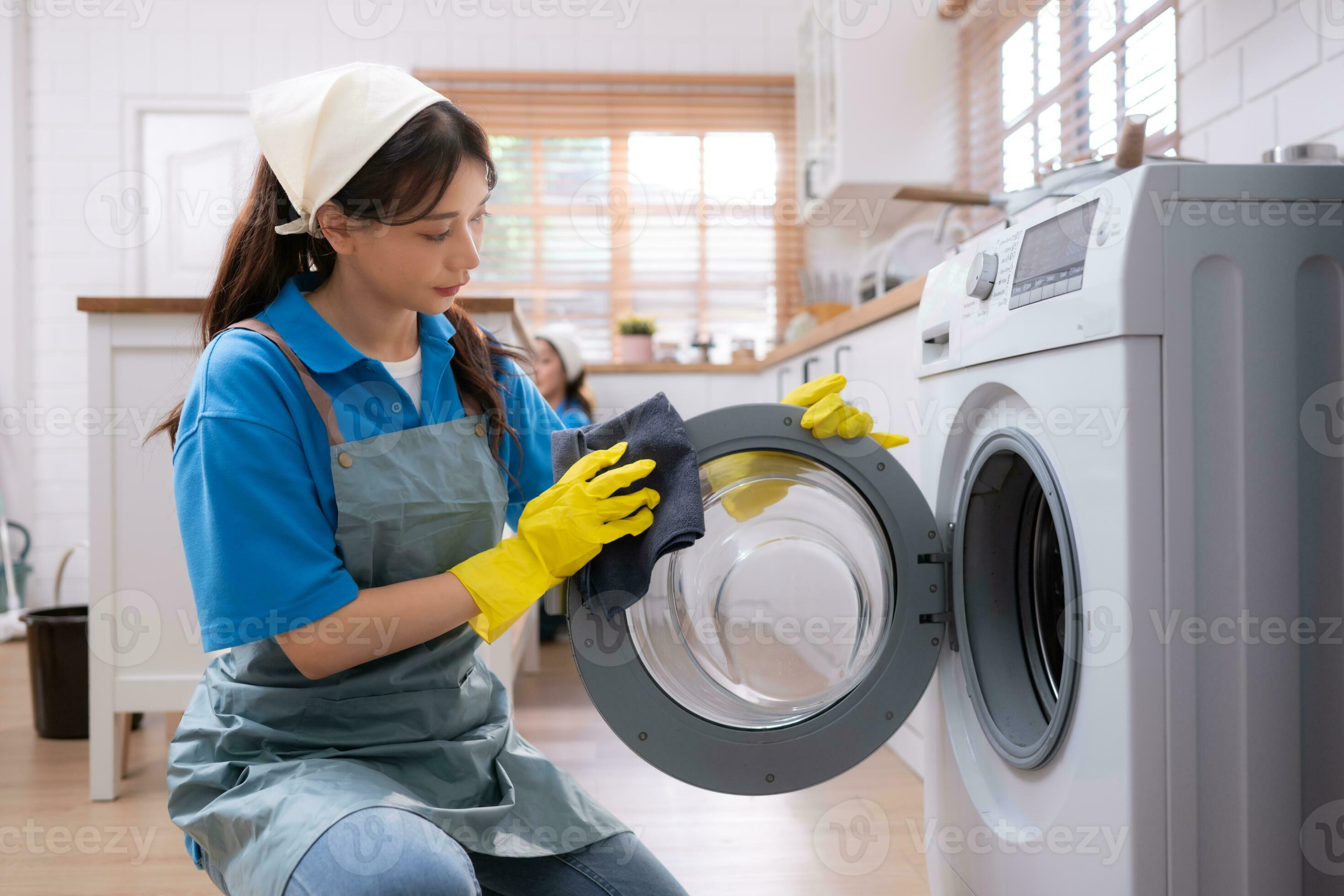 Asian young woman cleaning the washing machine in the kitchen