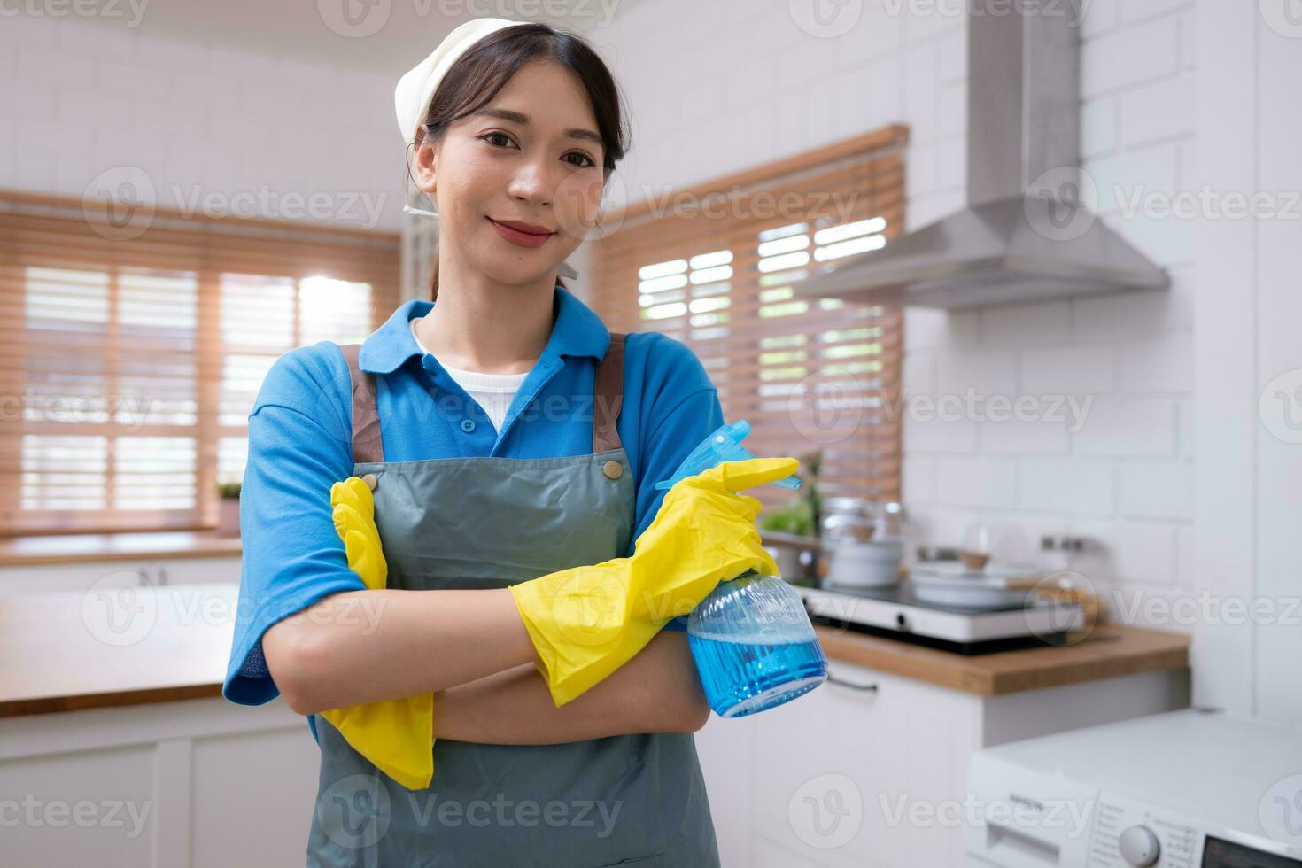 Asian housewife with cleaning cloth and spray bottle in the kitchen photo