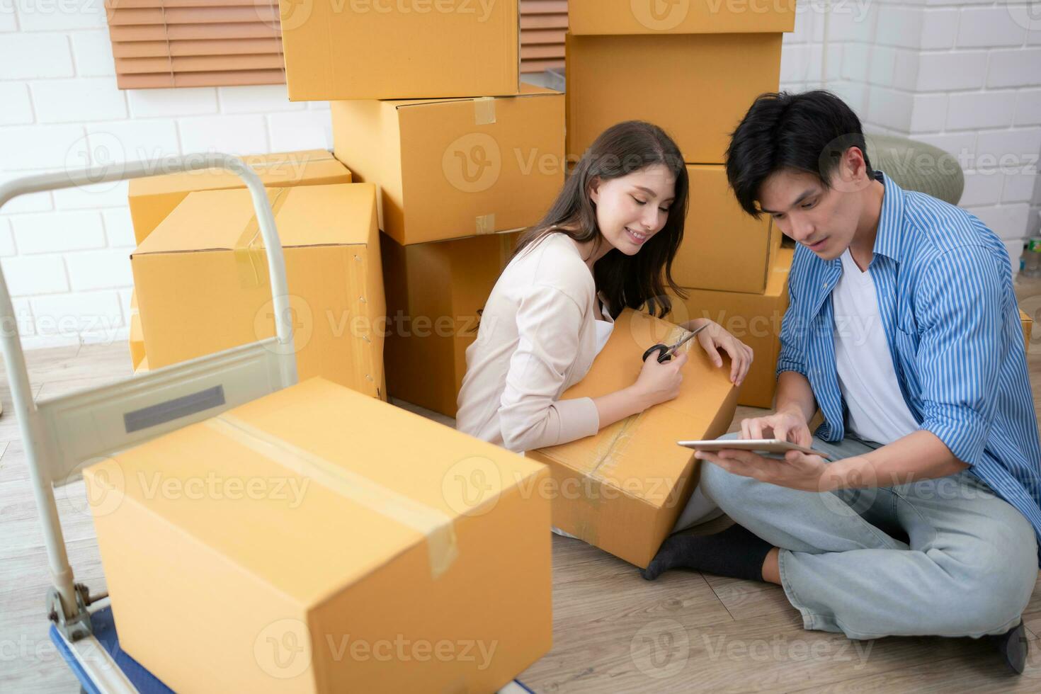 Young asian couple checking boxes being transported into new home with tablet photo