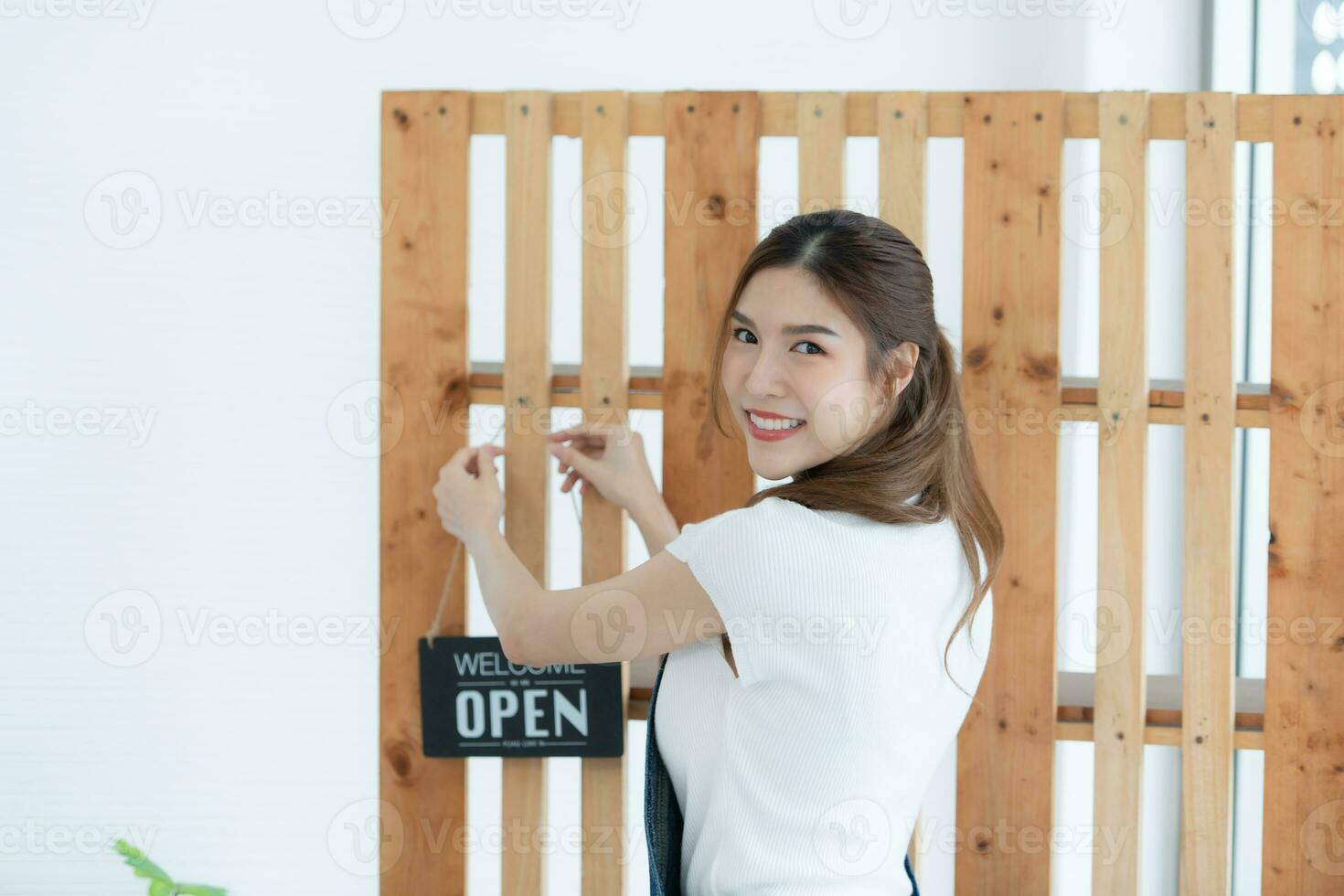 hermosa asiático mujer de negocios participación letrero con texto abierto en el tienda. foto