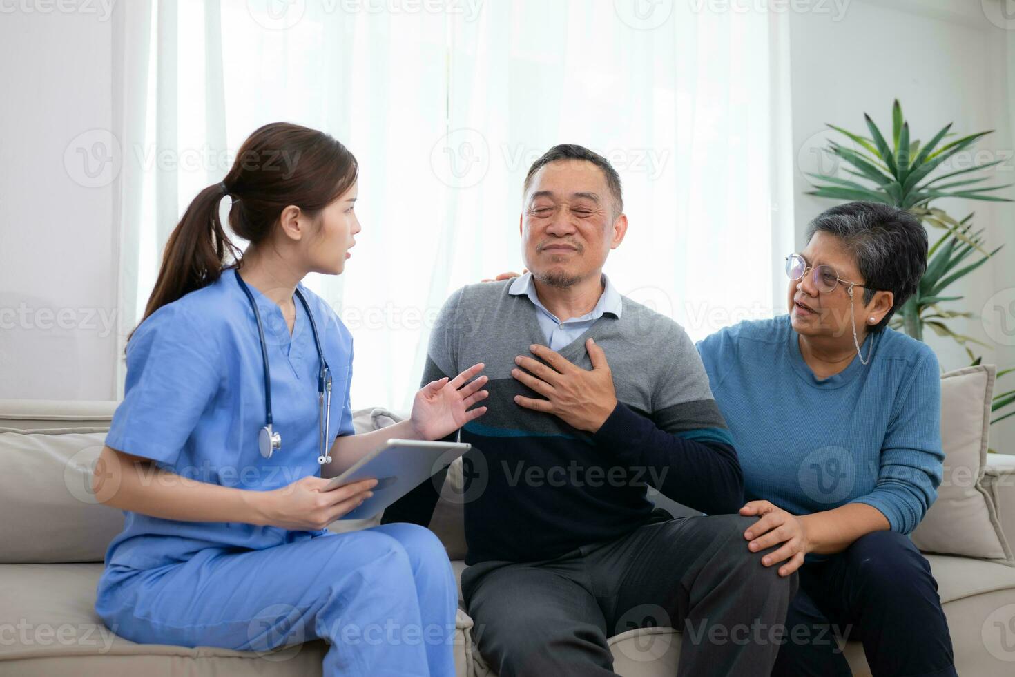 Asian senior patient talking with doctor and nurse on sofa at home photo