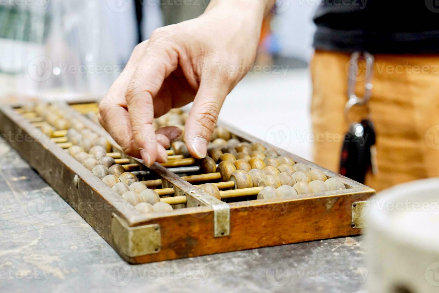 Closeup hand of person playing and demonstration used of ancient Chinese abacus on old black wooden table. photo