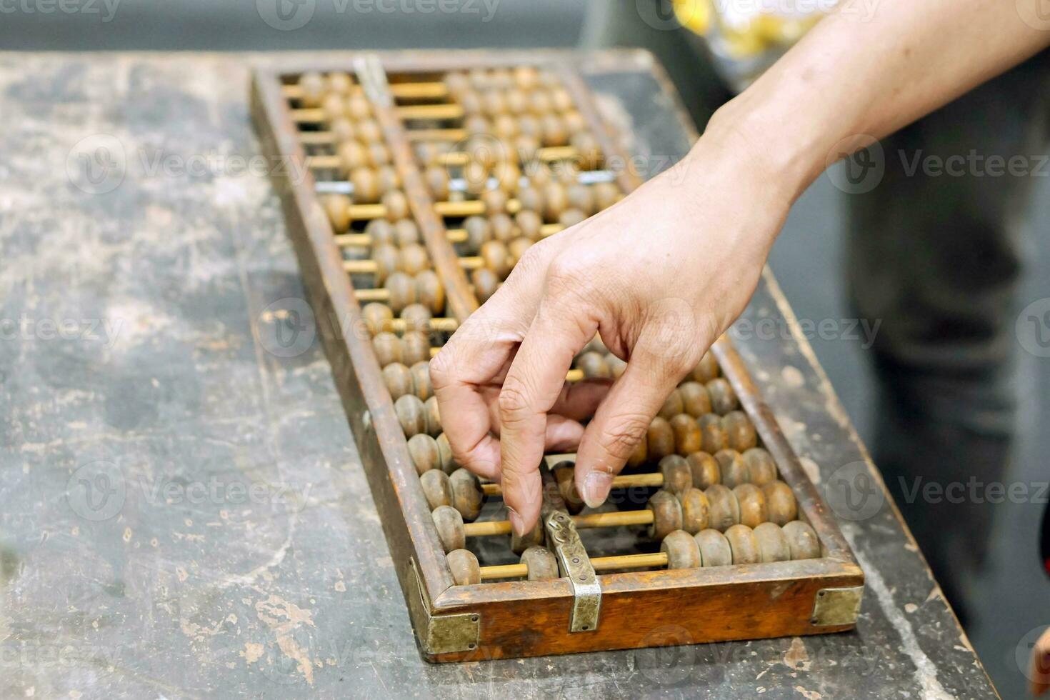 mano de persona jugando y demostración usado de antiguo chino ábaco en antiguo negro de madera mesa. foto