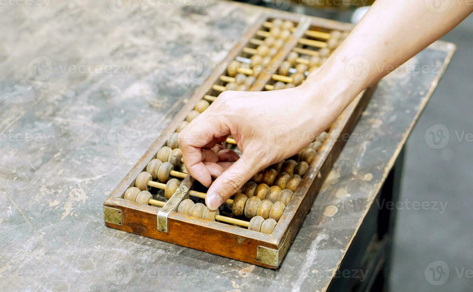 Hand of person playing and demonstration used of ancient Chinese abacus on old black wooden table. photo