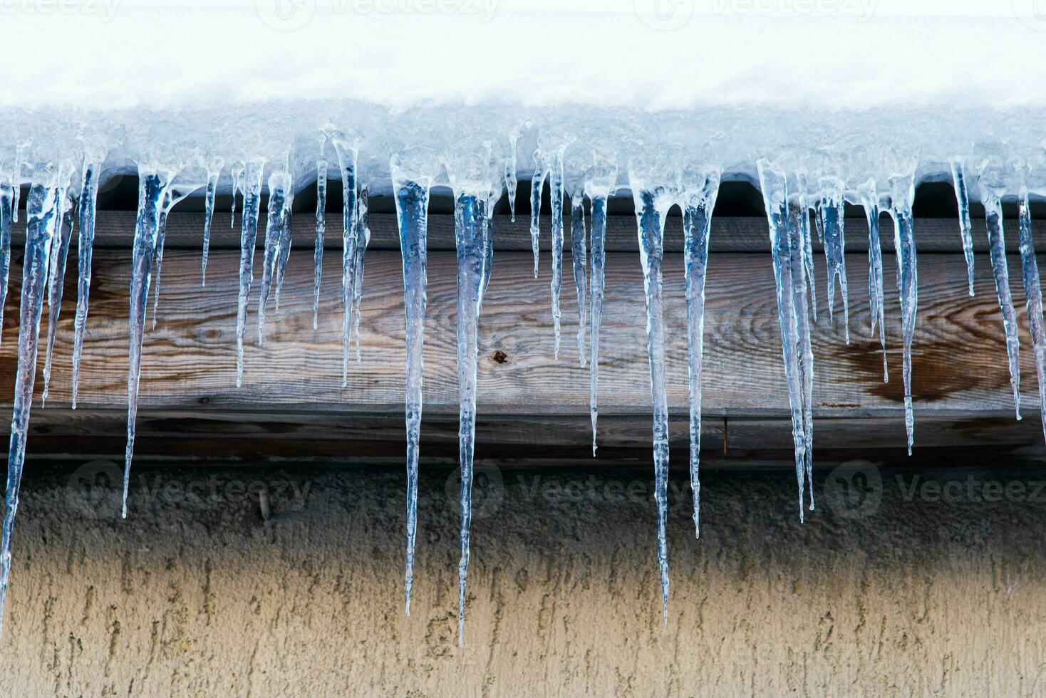 Icicles hang on a house roof. Snow melt from house roof warm winter day photo