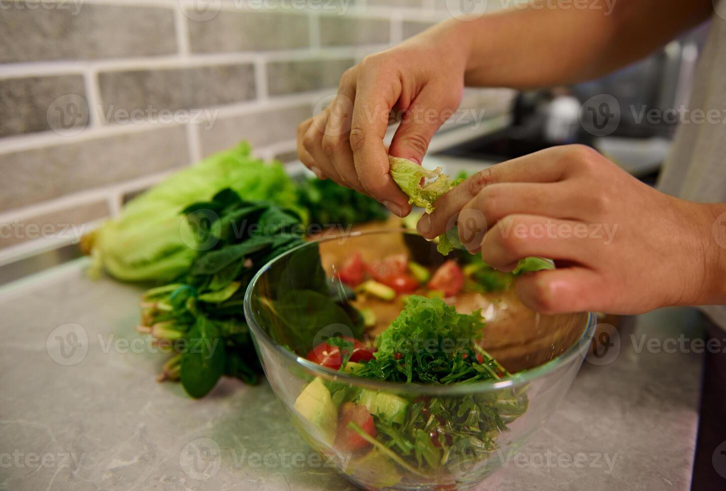 Healthy ingredients for raw vegan salad. Food and concept of veganism, vigor and healthy eating. Close-up of female chef hands preparing raw vegan salad at home kitchen. photo