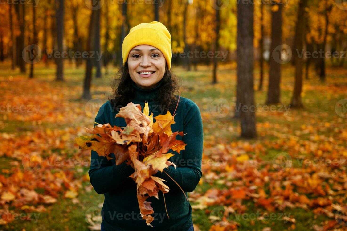 estilo de vida retrato de alegre mujer participación un seco recogido ramo de flores de otoño amarillo naranja vistoso caído hojas sonriente con dientes sonrisa mirando a cámara, posando en contra dorado otoño antecedentes foto