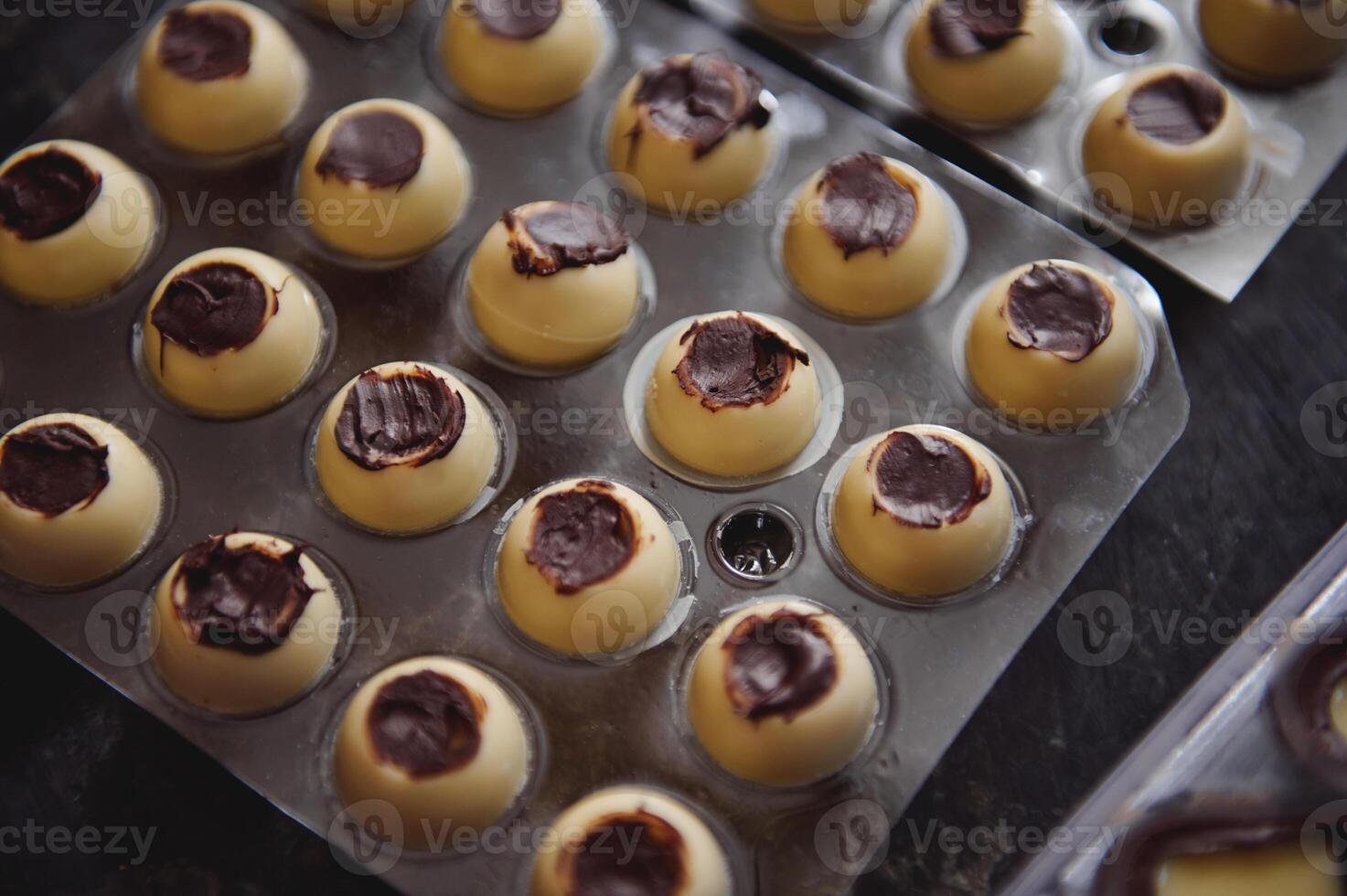 Closeup of manufacturing chocolate truffles. Spherical molds of white