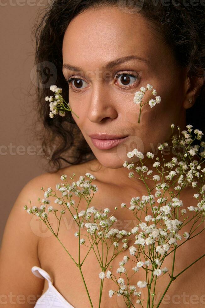 belleza retrato de un hermosa confidente sereno pelinegro Hispano mujer con blanco Gypsophila puntilla. cuerpo cuidado, positividad, sensualidad, confianza, auto-aceptación, feminidad, De las mujeres día concepto foto