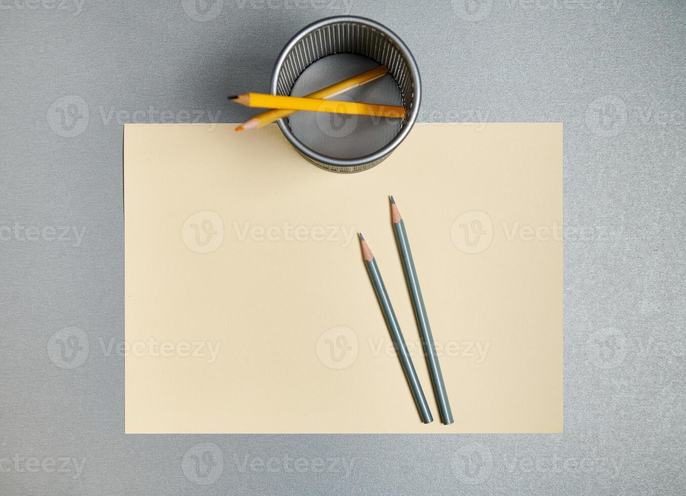 Pencils and pencil holder on a yellow paper on gray background. Flat lay. Top view photo