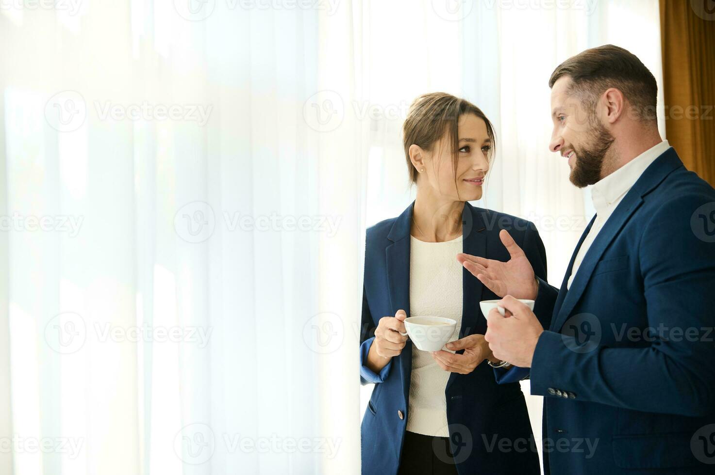 dos negocio socios hablando a cada otro terminado un taza de café, en pie por el ventana. concepto de exitoso negociaciones, Servicio relación, negocio y camaradería. Copiar espacio para anuncios foto