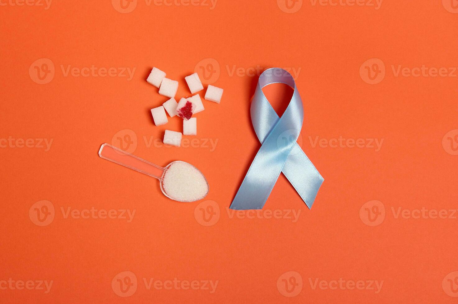 puro refinado blanco azúcar cubitos con sangre soltar y azul satín cinta, símbolo de mundo diabetes conciencia día 14 noviembre. aislado terminado de colores naranja fondo, Copiar espacio para médico anuncio. plano laico foto