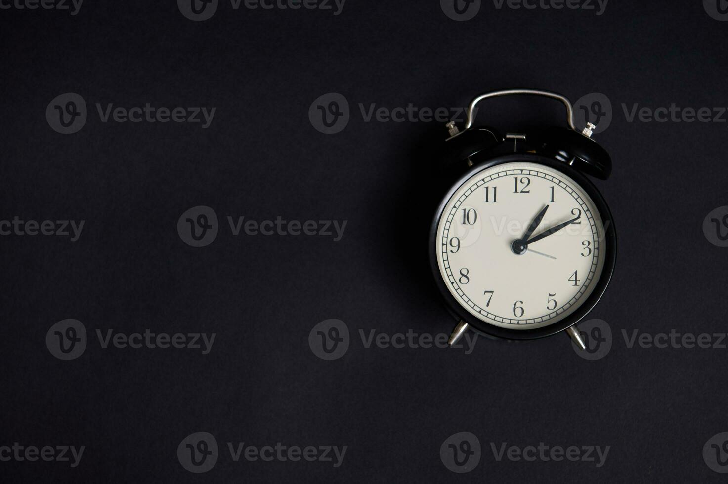 Flat lay. Monochrome composition with a vintage alarm clock on black background with copy space to add text. Back to School and Teachers Day Concepts, Business, Organization, Time Management photo