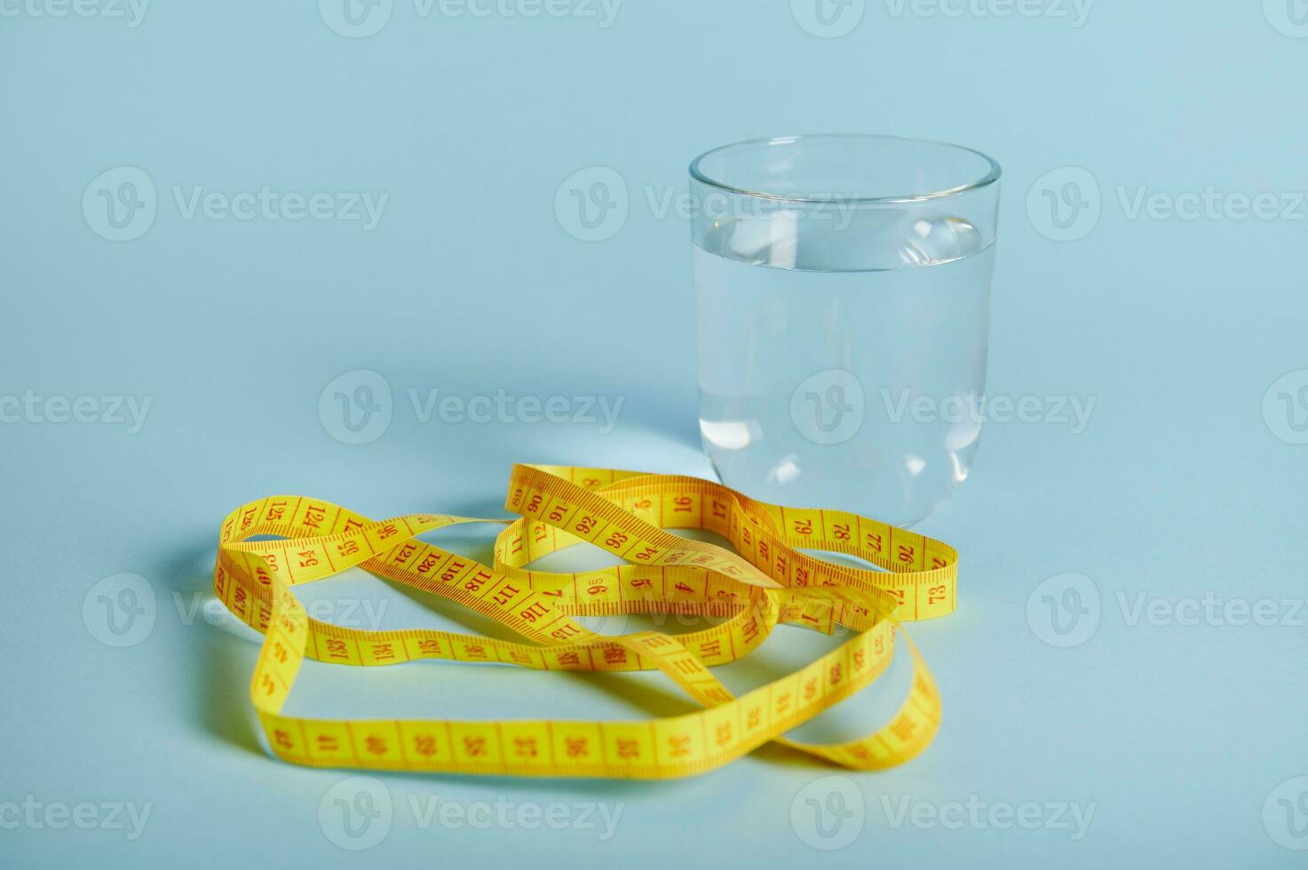 un vaso con agua y un medición cinta aislado en azul antecedentes con espacio para texto foto