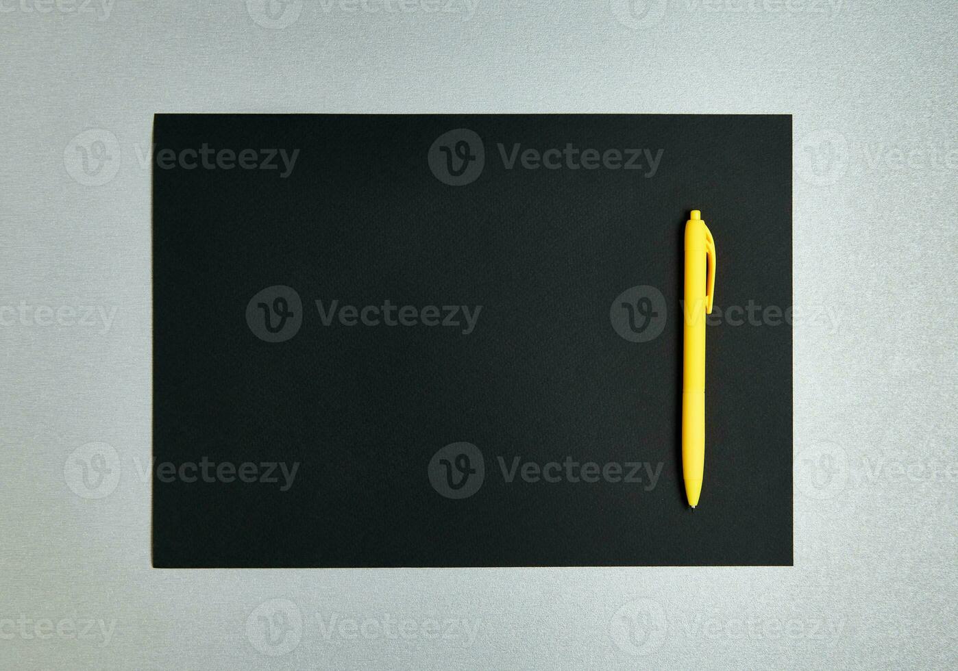 Flat lay composition with yellow pen on a black designer paper on a gray background. Top view photo