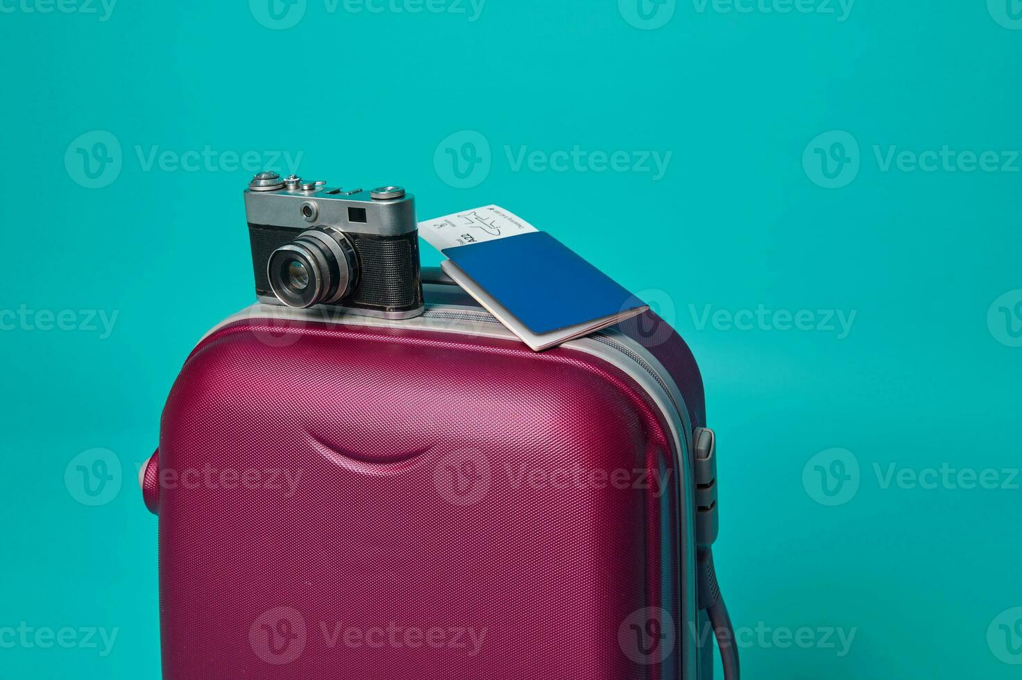 Close-up. Vintage camera and passport with ticket and boarding pass on a suitcase luggage, isolated over blue background with copy ad space photo