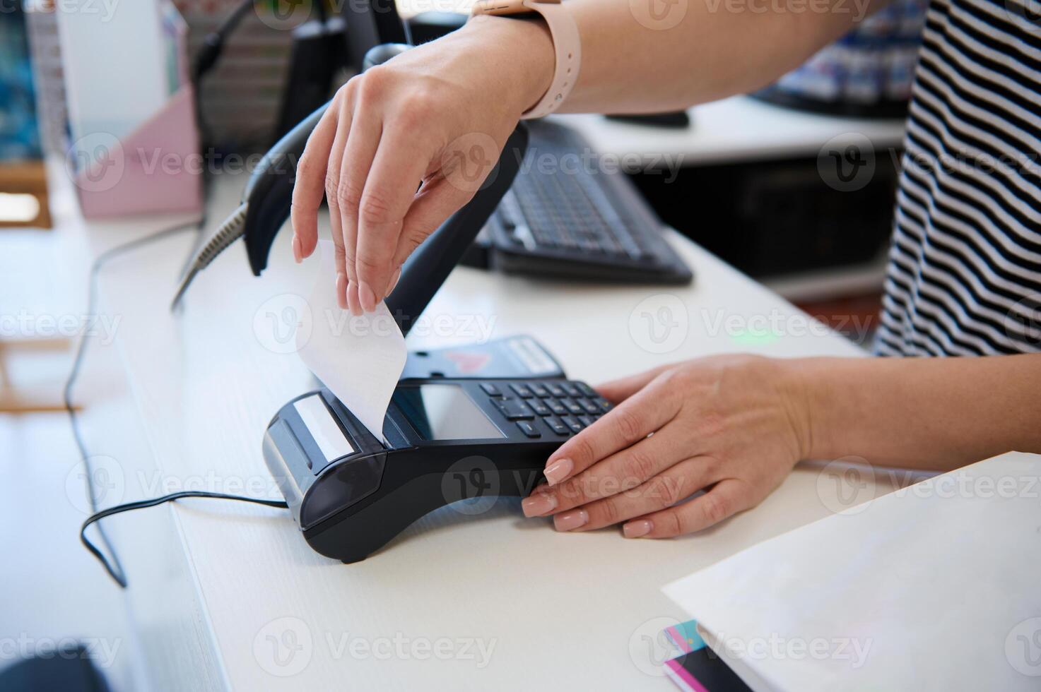 Close-up salesperson using POS terminal in a store, receiving a cashless payment and taking out a receipt for a purchase photo