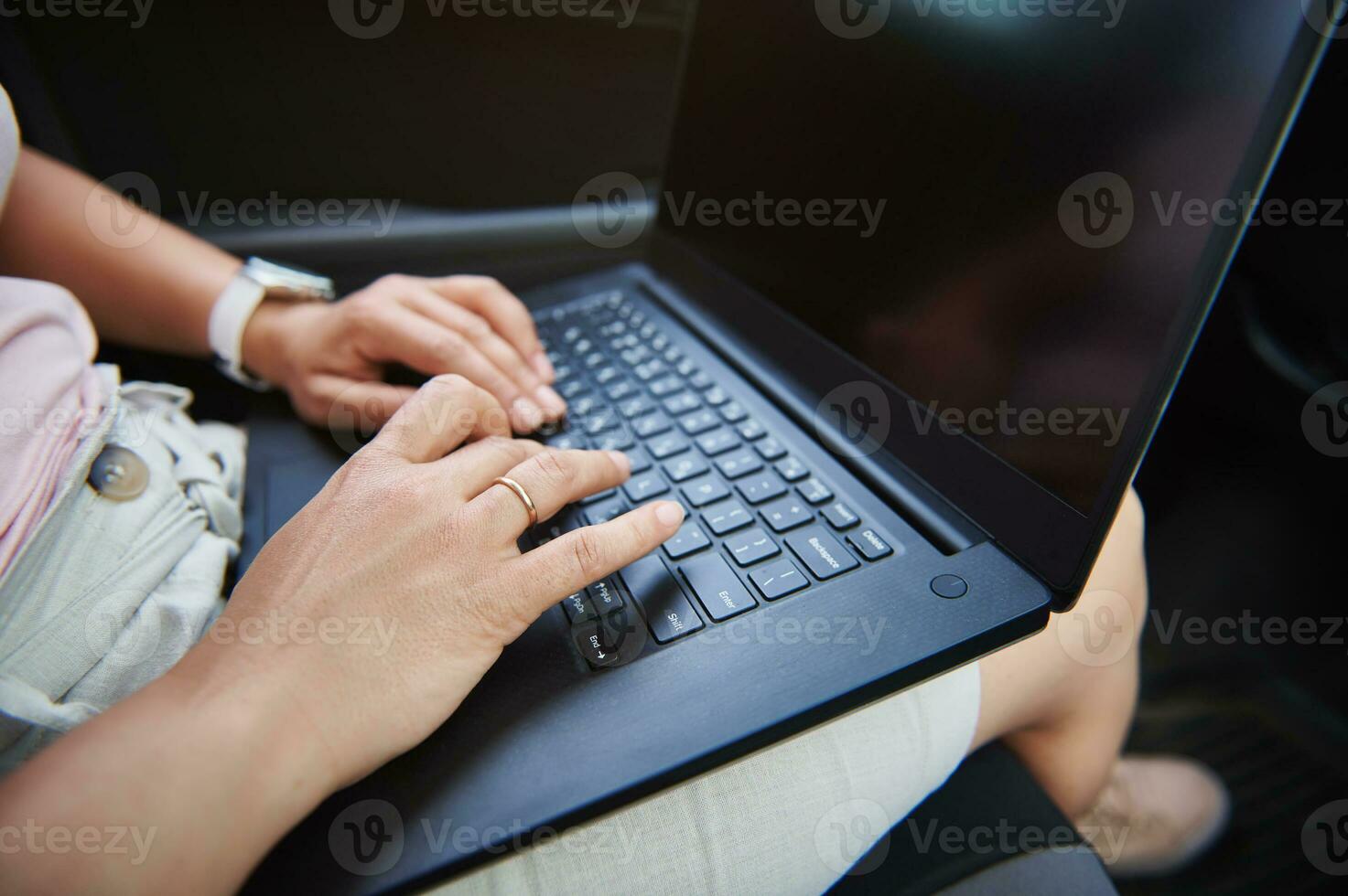 Close-up image of business woman hands typing a text message on laptop while sitting in driver seat in the car photo