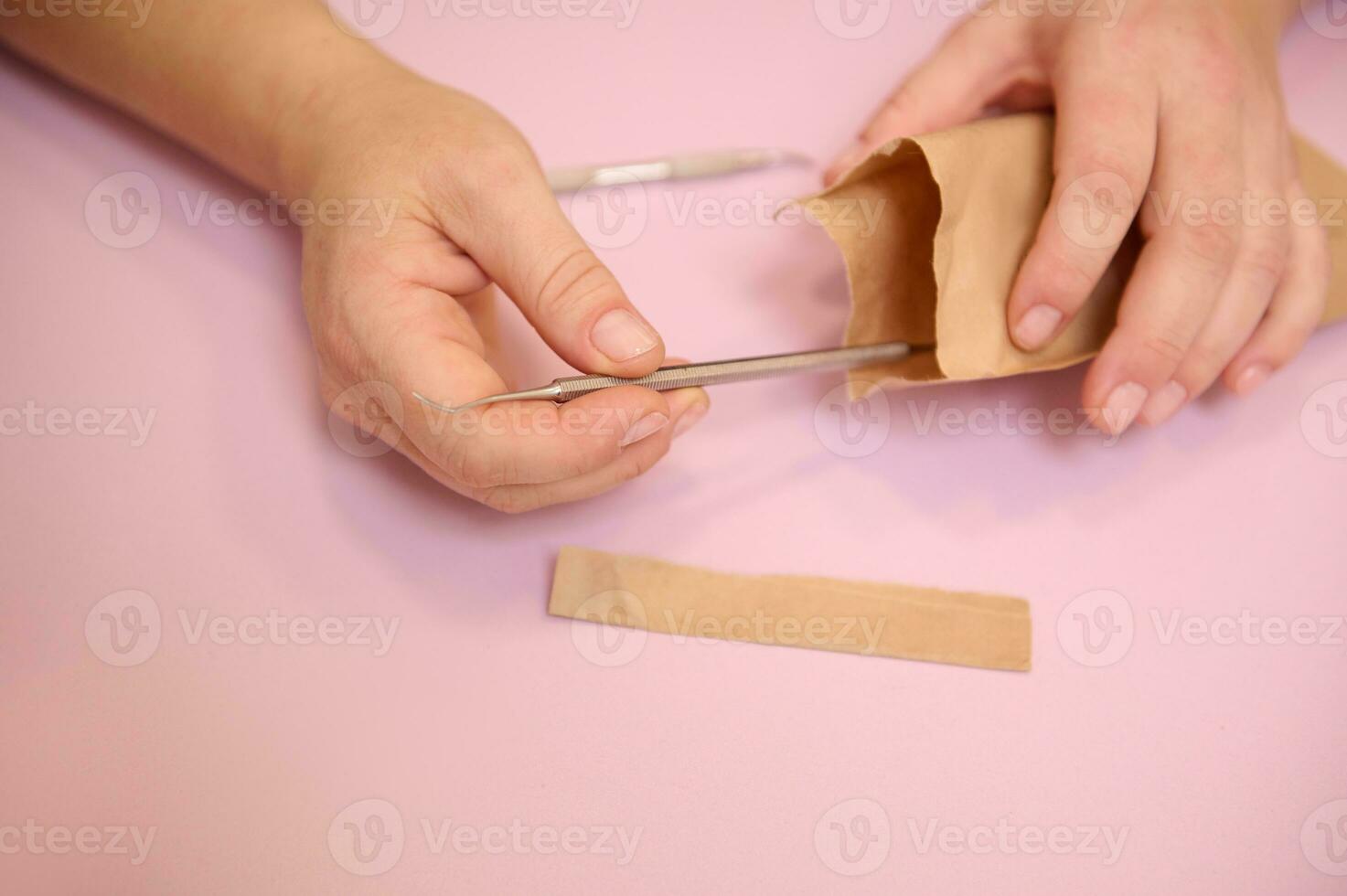 Podiatrist hands opening a bag with sterile stainless steel instruments for a professional pedicure. Close-up photo