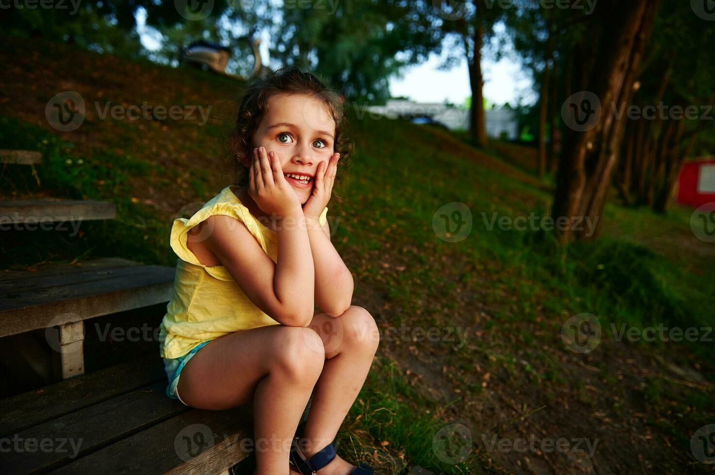 Beautiful and cheerful baby girl sitting on a wooden step by the lake pier. photo