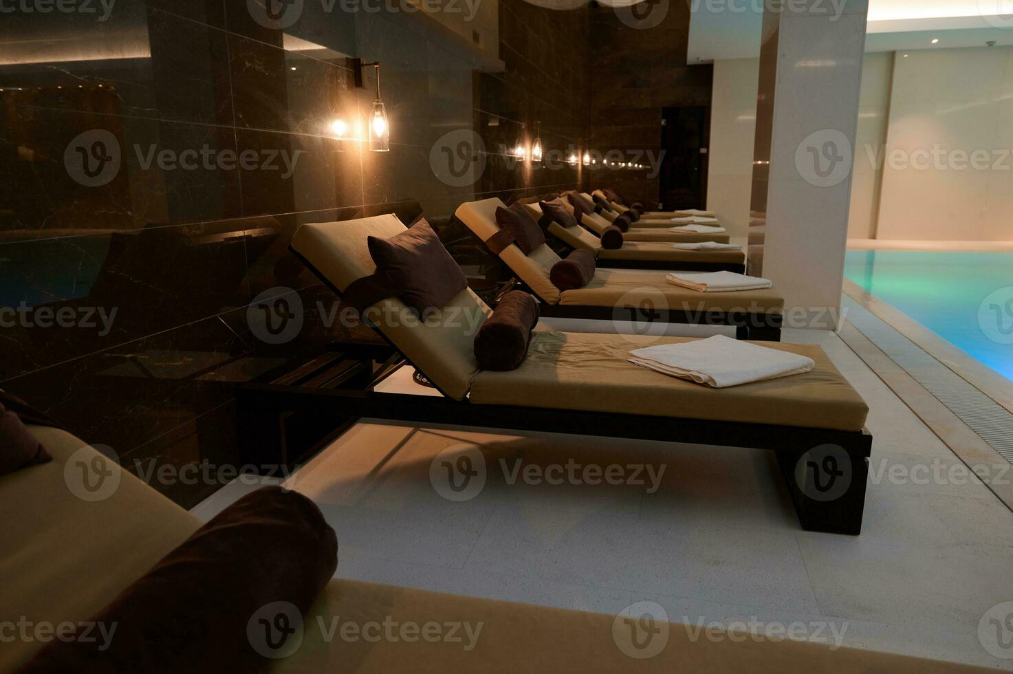 View of loungers in spa room with swimming pool in hotel and wellness spa resort. Interior design photo