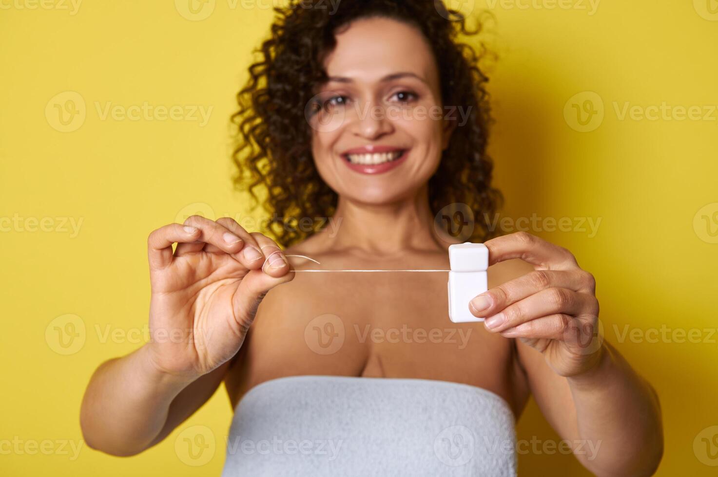 Soft focus on hygiene dental floss in hands of smiling woman with beautiful toothy smile photo