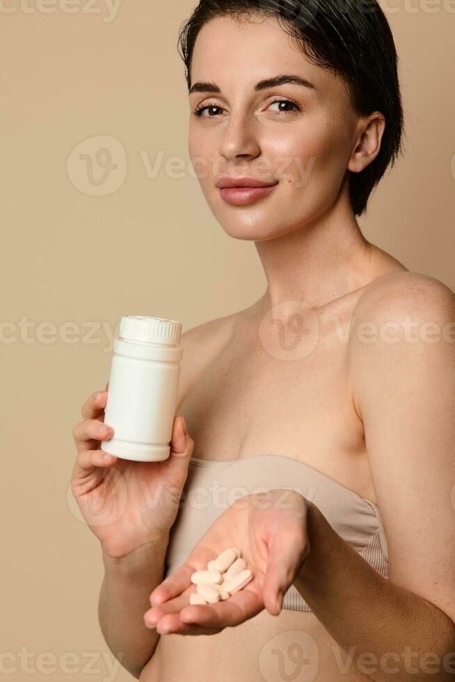 bonito mujer participación un botella con dietético suplemento, vitaminas y minerales y demostración algunos pastillas en su manos, lindo sonriente mirando a cámara. salud, piel y cuerpo cuidado concepto foto