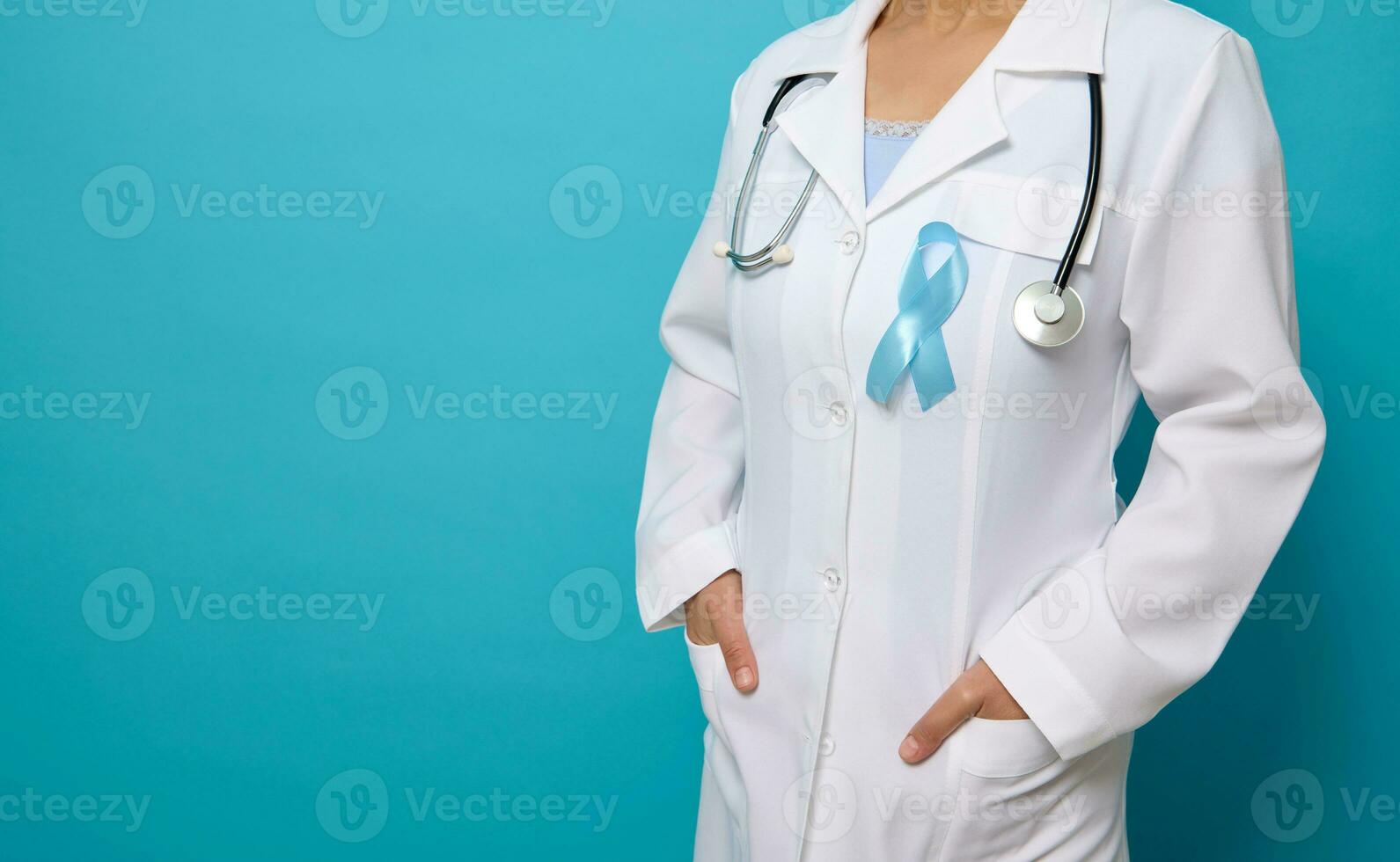 Close-up, cropped studio shot of female doctor in white medical gown wearing blue satin ribbon, symbolic bow color raising awareness in diabetes day . Medical concept for 14 November with copy space photo