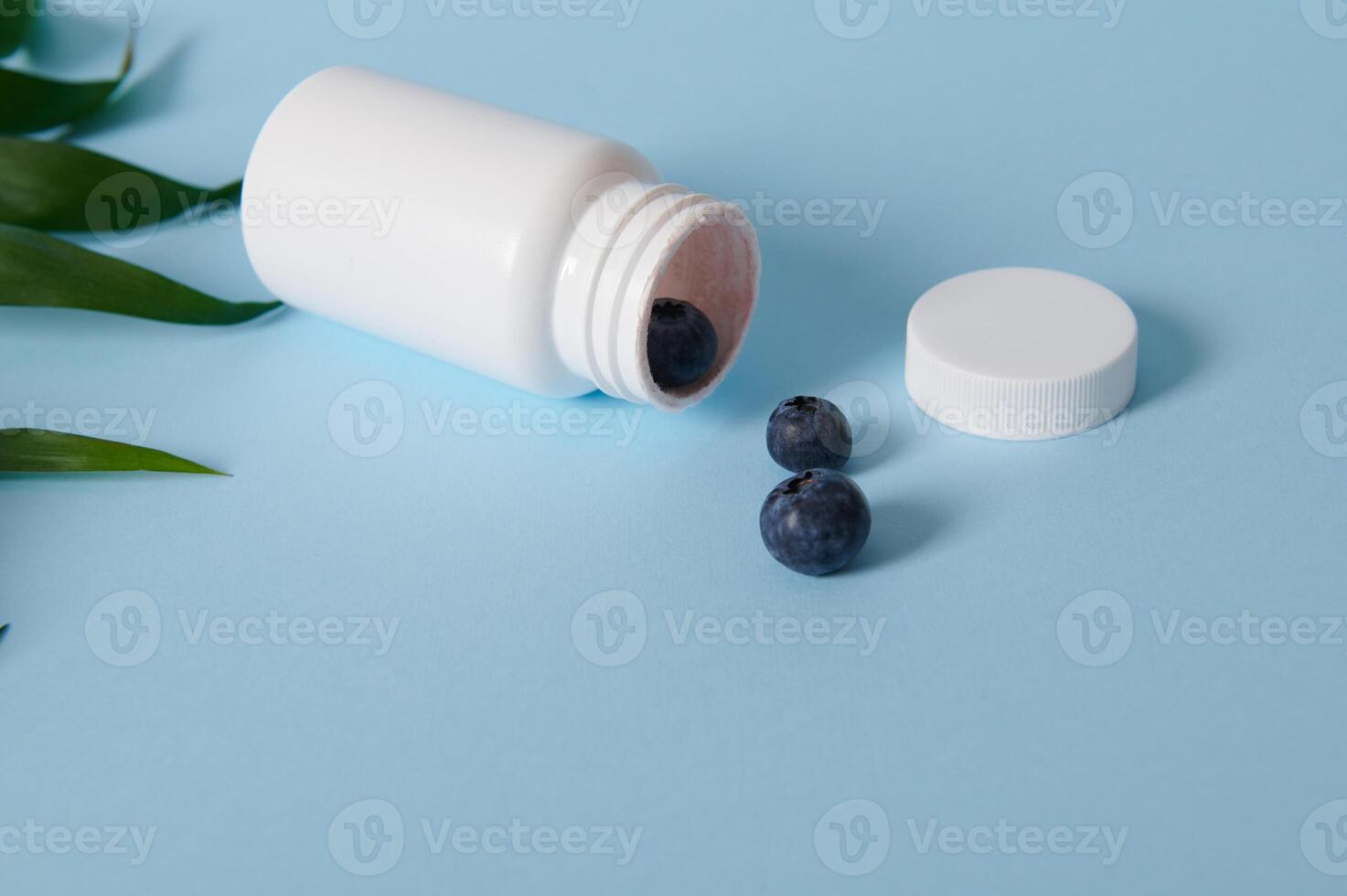 High angle view of blueberries scattered from an opened white container on blue background photo