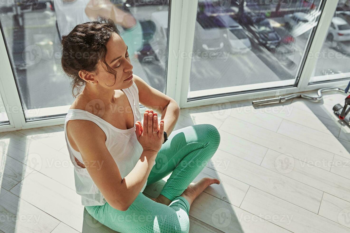 alto ángulo ver de un atractivo mujer ejecutando padmasana, inhalando aire y haciendo respiración ejercicios durante yoga práctica a hogar foto