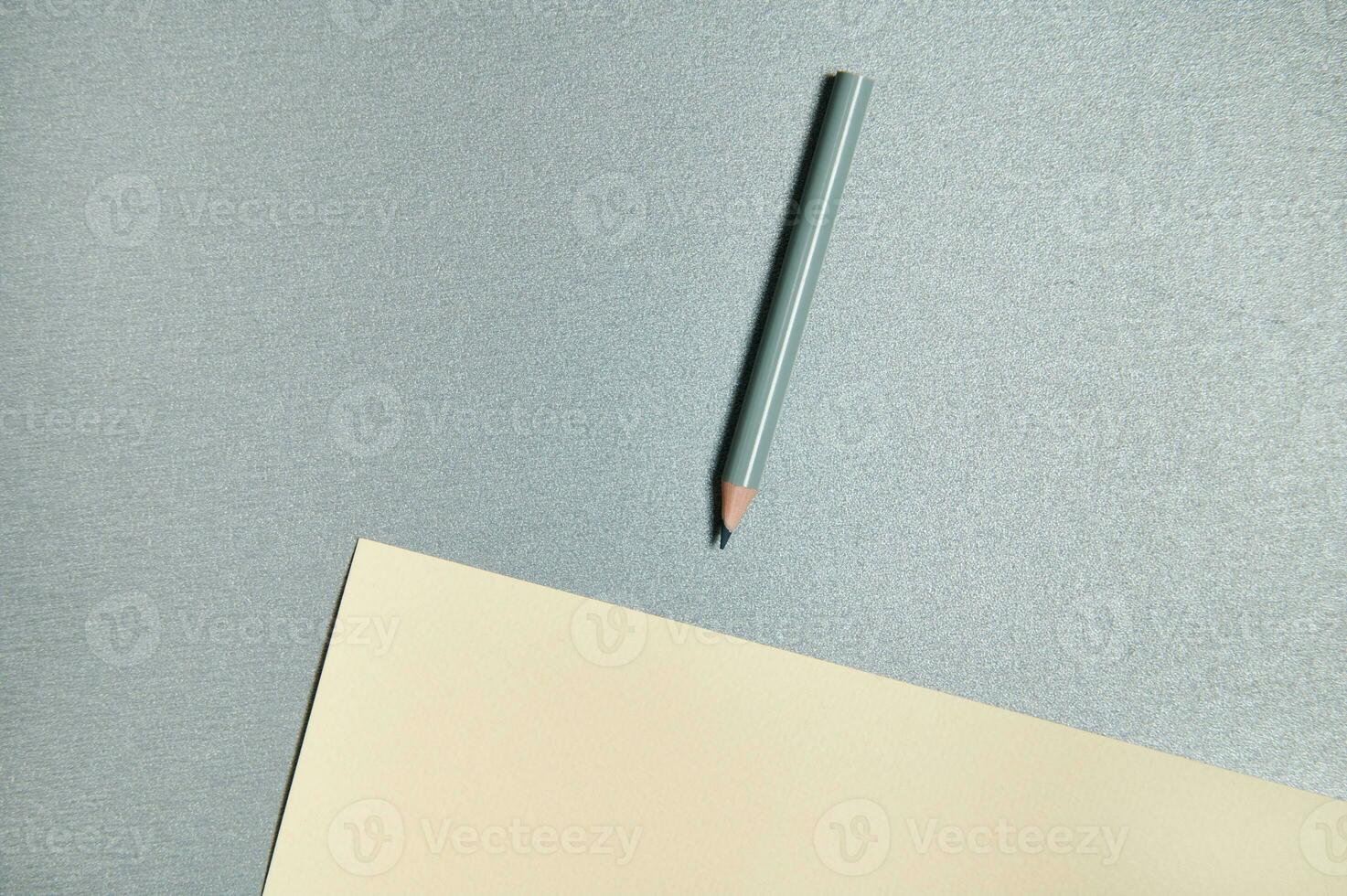 Top view of drawing tools on gray background. Gray color pencil and yellow designer paper photo