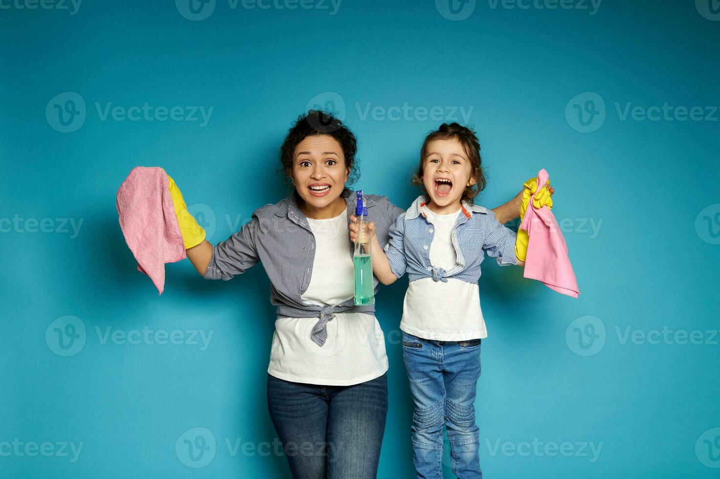 mujer y niño posando en un azul antecedentes con limpieza productos en manos. limpieza concepto, familia relaciones foto