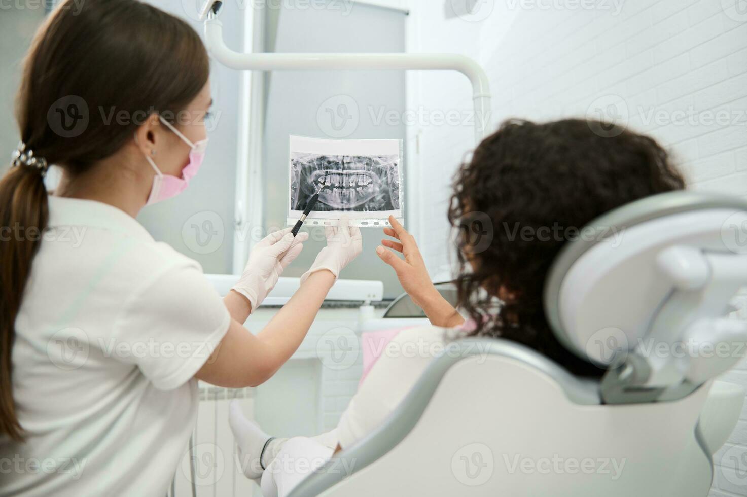 posterior ver a hembra dentista demostración paciente panorámico dental radiografía durante médico chequeo en un moderno dental clínica y explicando consulta tratamiento asuntos. médico diagnósticos en odontología foto