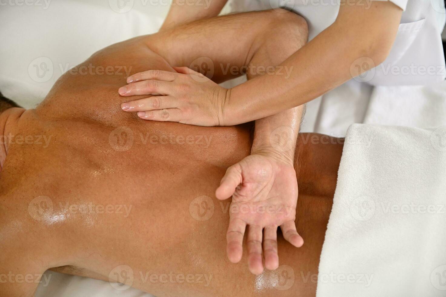 Close-up of unrecognizable professional masseuse massaging male back in spa. Alternative body treatment concept photo