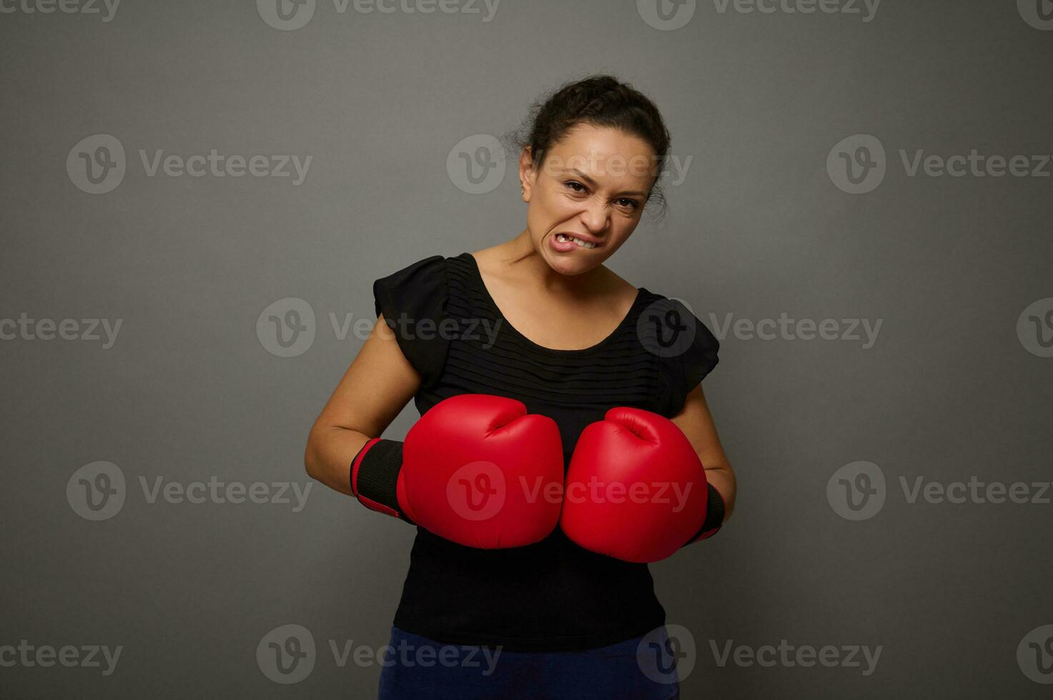 Strong African woman poses against gray wall background with red boxing gloves. Concept of Black Friday and boxing Day, Blow to prices with copy space for advertisement photo