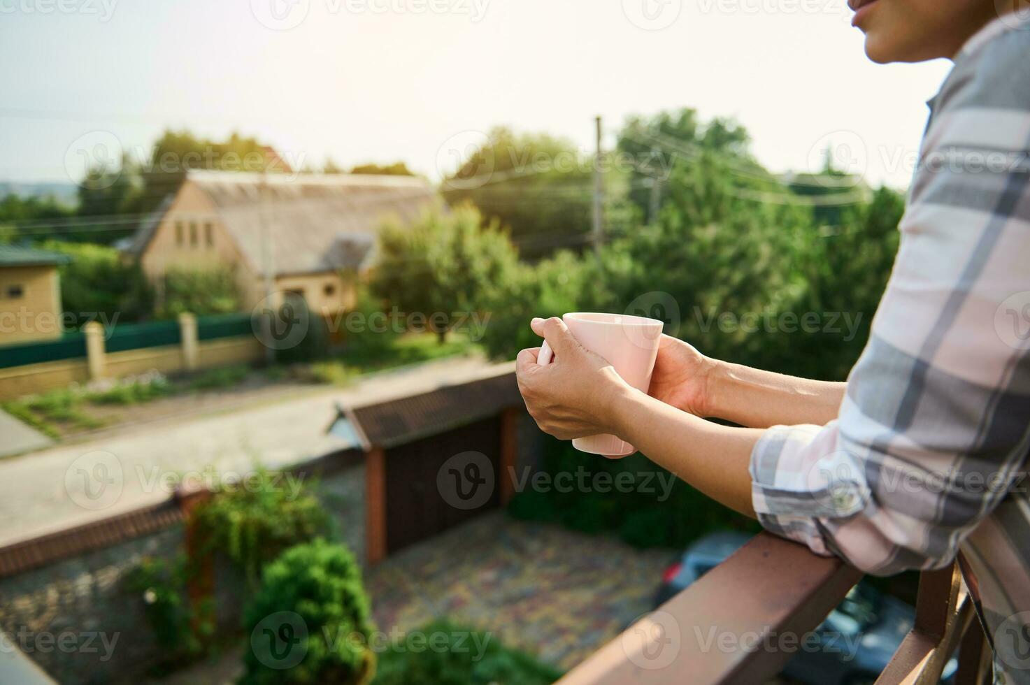 Focus on female hands holding cup of hot drink, on the balcony photo