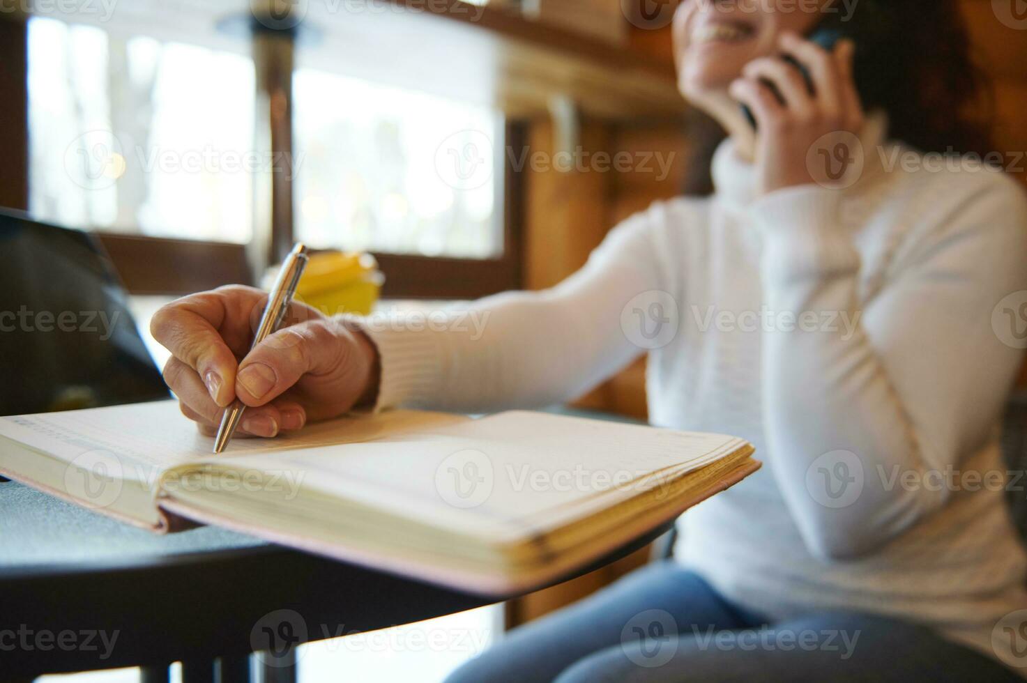 de cerca de mujer mano participación un plata bolígrafo y escritura en un lechería a un de madera cafetería bar foto