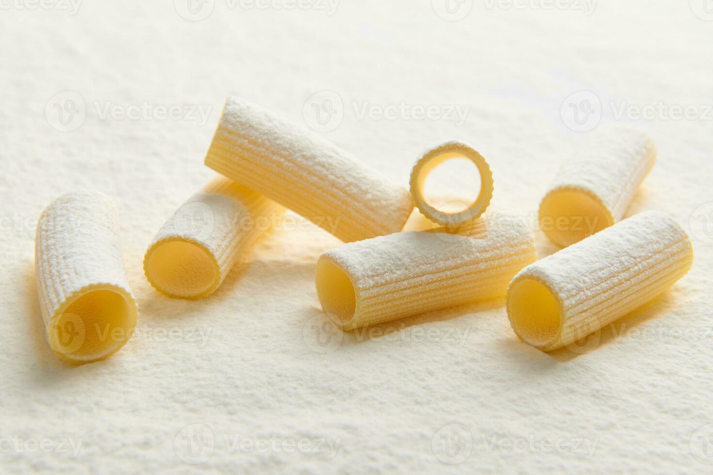 Studio shot with soft shadow of raw Italian pasta- whole wheat tortiglioni on white background with scattered flour. Copy space for food advertisement photo