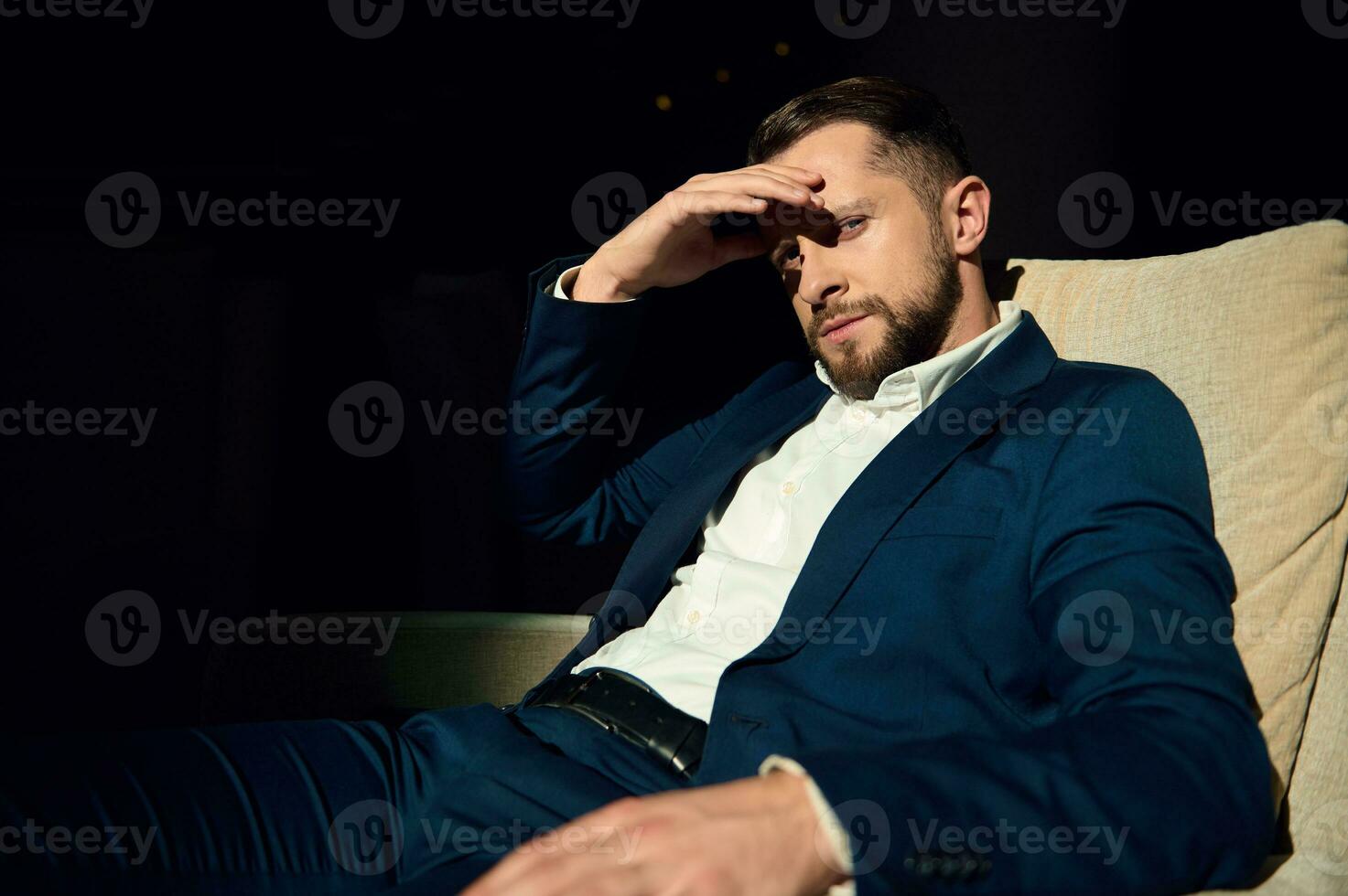 Successful businessman, business traveler, investor sitting relaxed in armchair with crossed legs, exhausted after meetings and negotiations, waiting for a transfer to airport photo