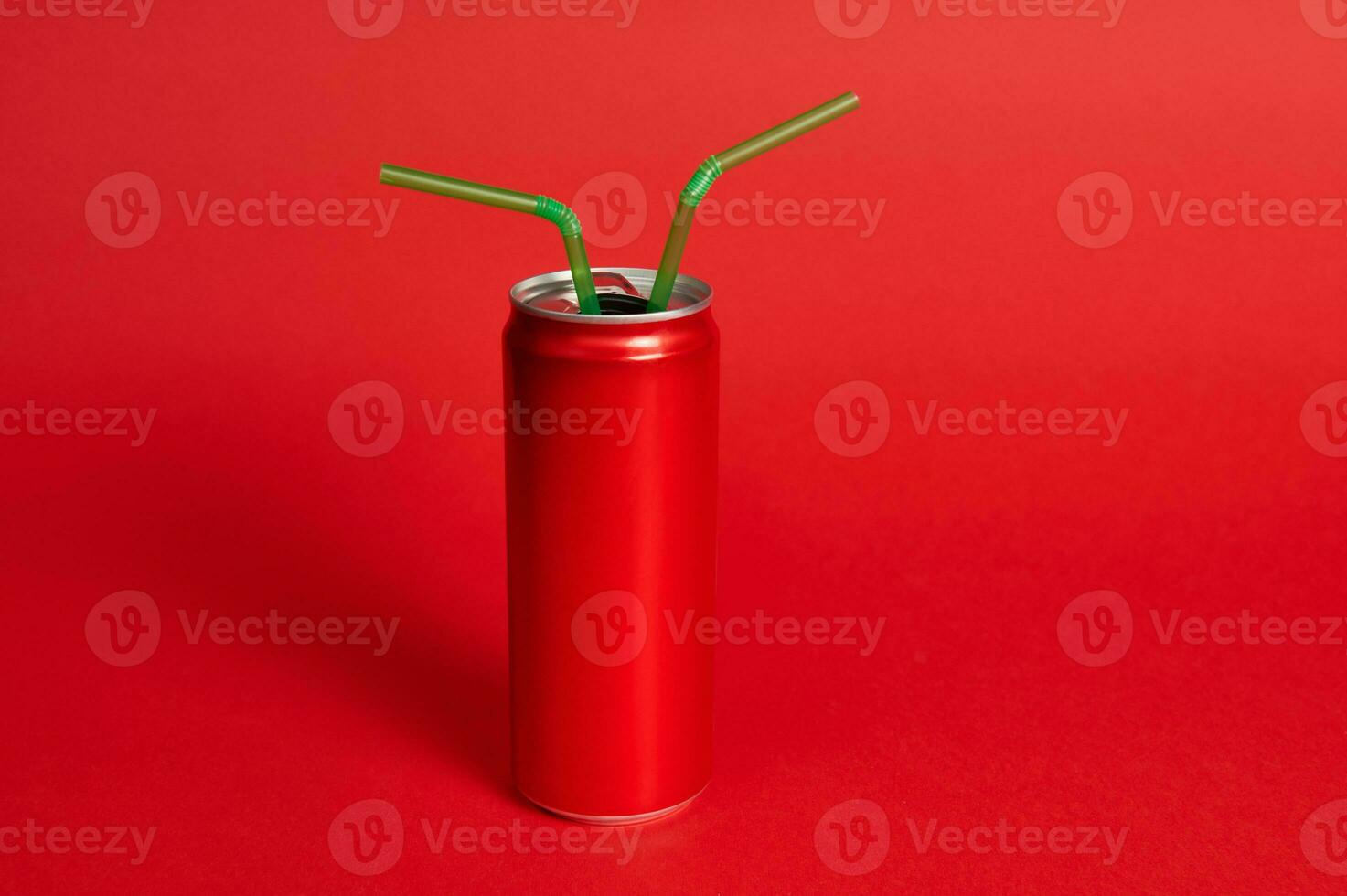 A studio shot with a soft shadow of a red metal can with the ring pul and two green straws on a red background. Green-Red, color contrast photo