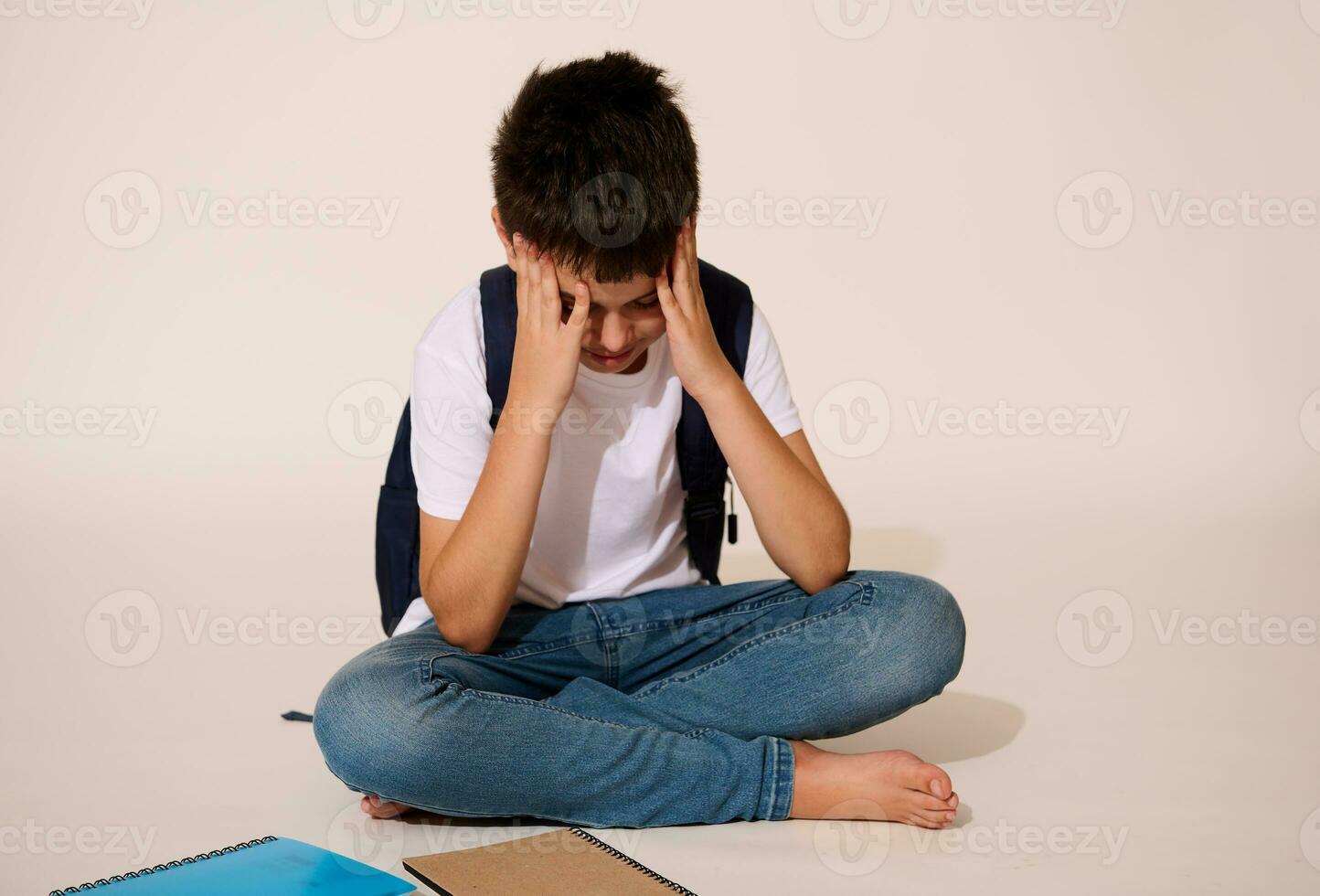 Hispanic teen boy holding head, feeling bored, unhappy, tired after hard day at school, isolated over white background photo