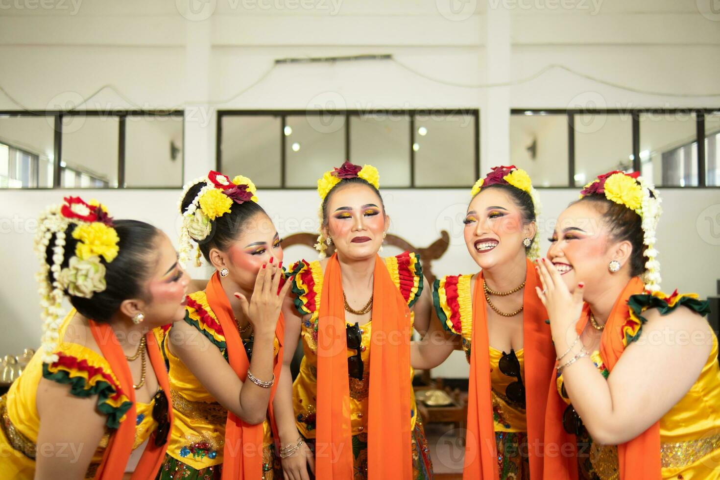 a group of traditional Javanese dancers laughing together with ridiculous faces and full of joy while on stage photo